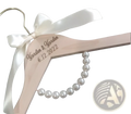 Personalized light pink wooden wedding dress hanger with white satin bow, engraved garden garden 6.12.2022, and pearl beads