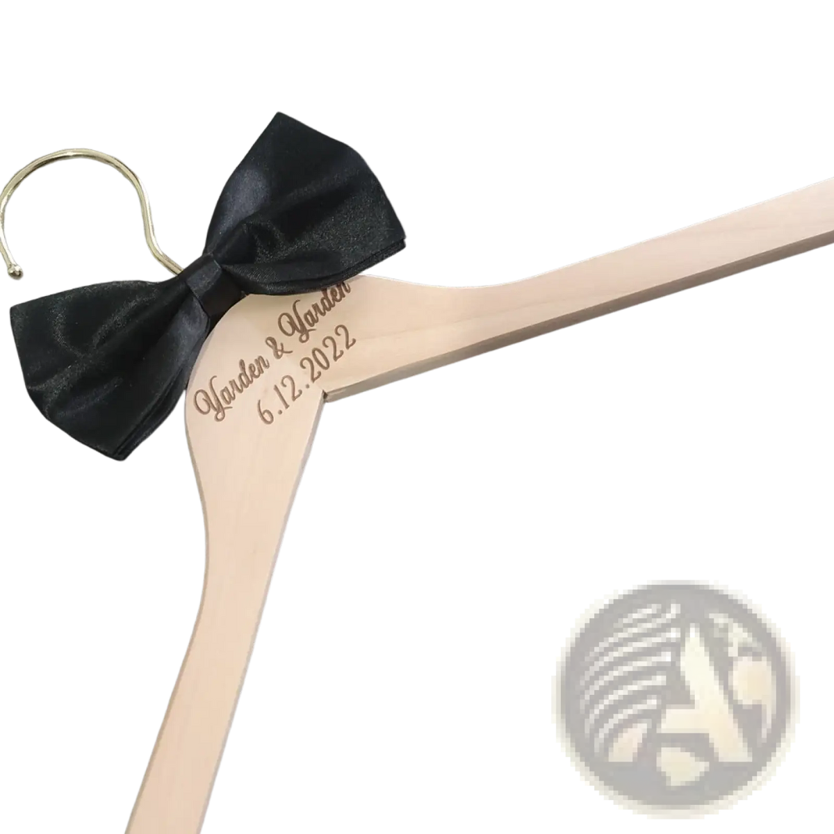 A light-colored wooden personalized wedding dress hanger with black satin bow engraved with harden and harden and date