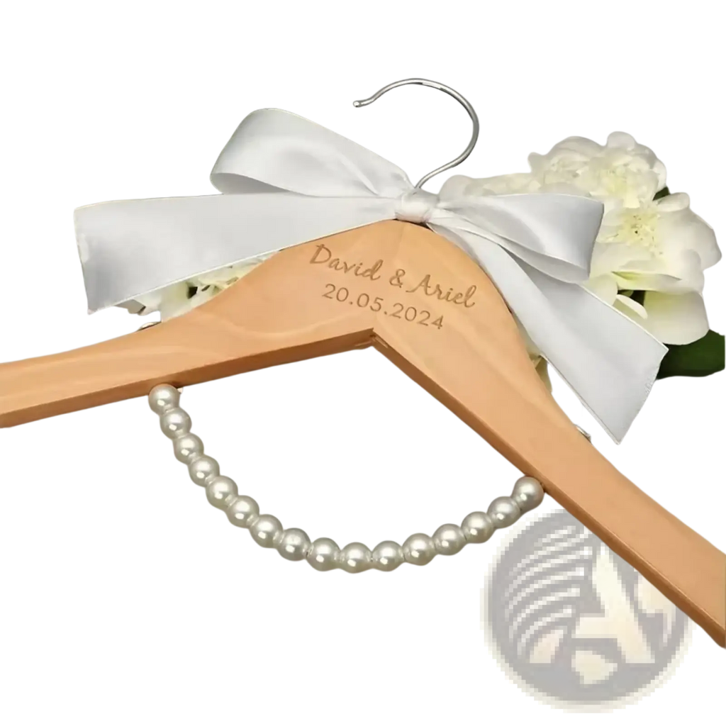 A light wood personalized wedding dress hanger with silver hook, engraved inscription, and white satin bow