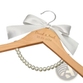 A light wood personalized wedding dress hanger engraved with david and ariel 20.05.2024 and white satin bow