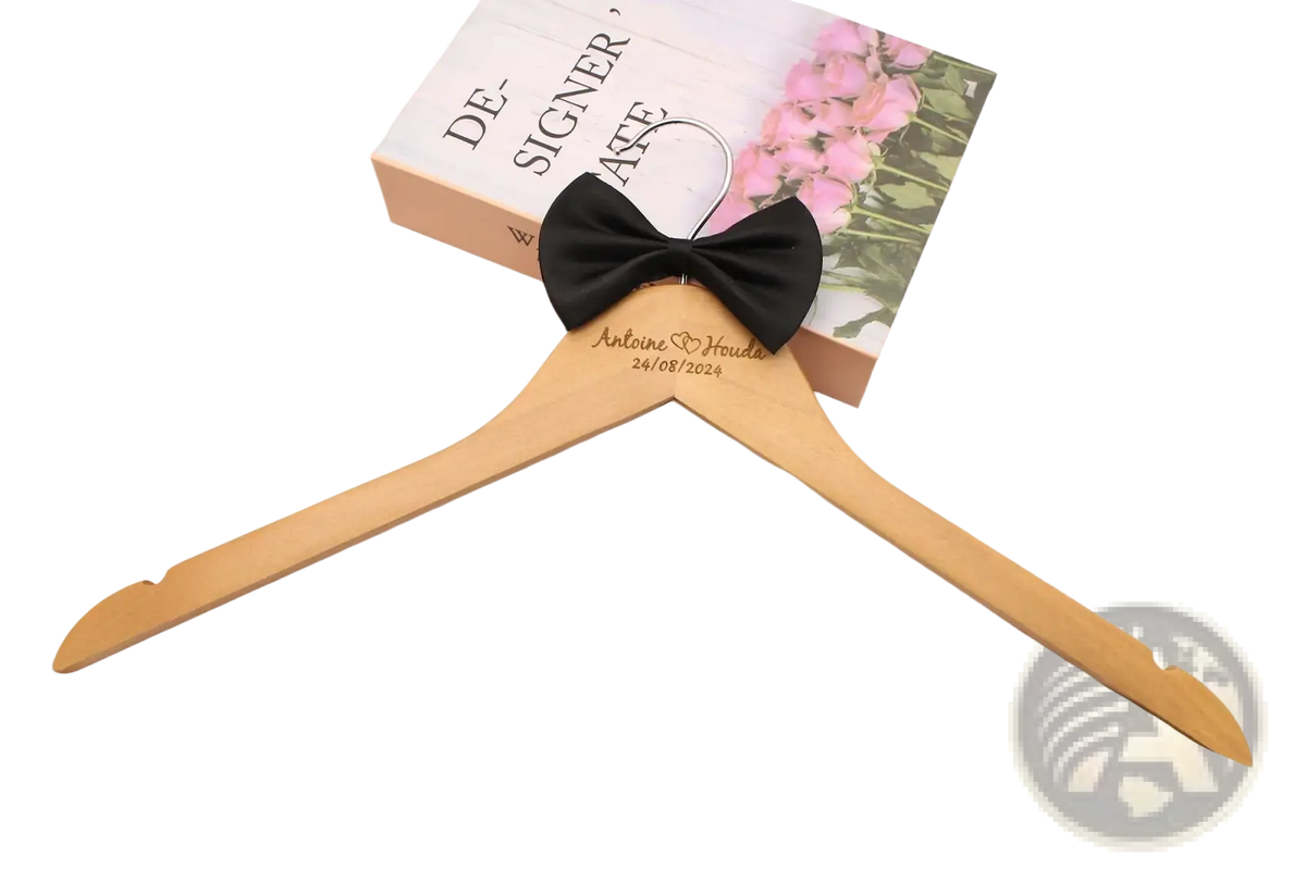 Personalized wedding dress hanger made of light wood engraved with names and date adorned with a black satin bow
