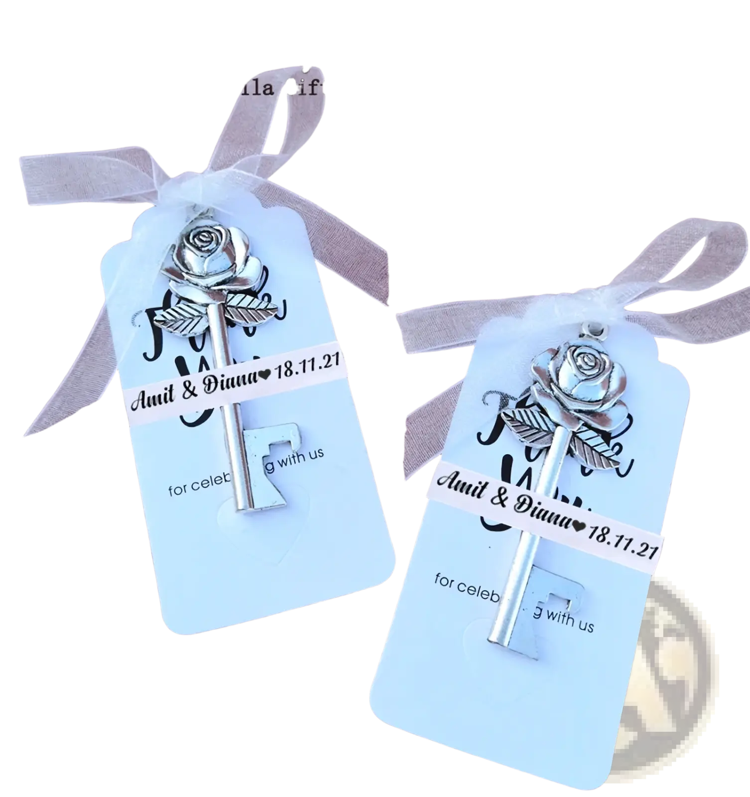 Silver rose key charm with metallic finish attached to white ribbon on light blue gift tags for personalized wedding favors