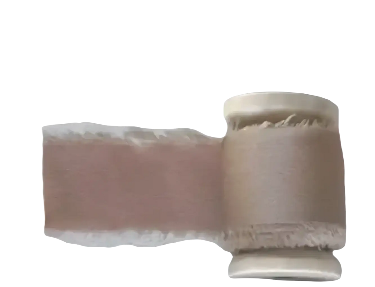 A roll of beige textured fabric with frayed edge and stitching for personalized his and her wedding vow books set