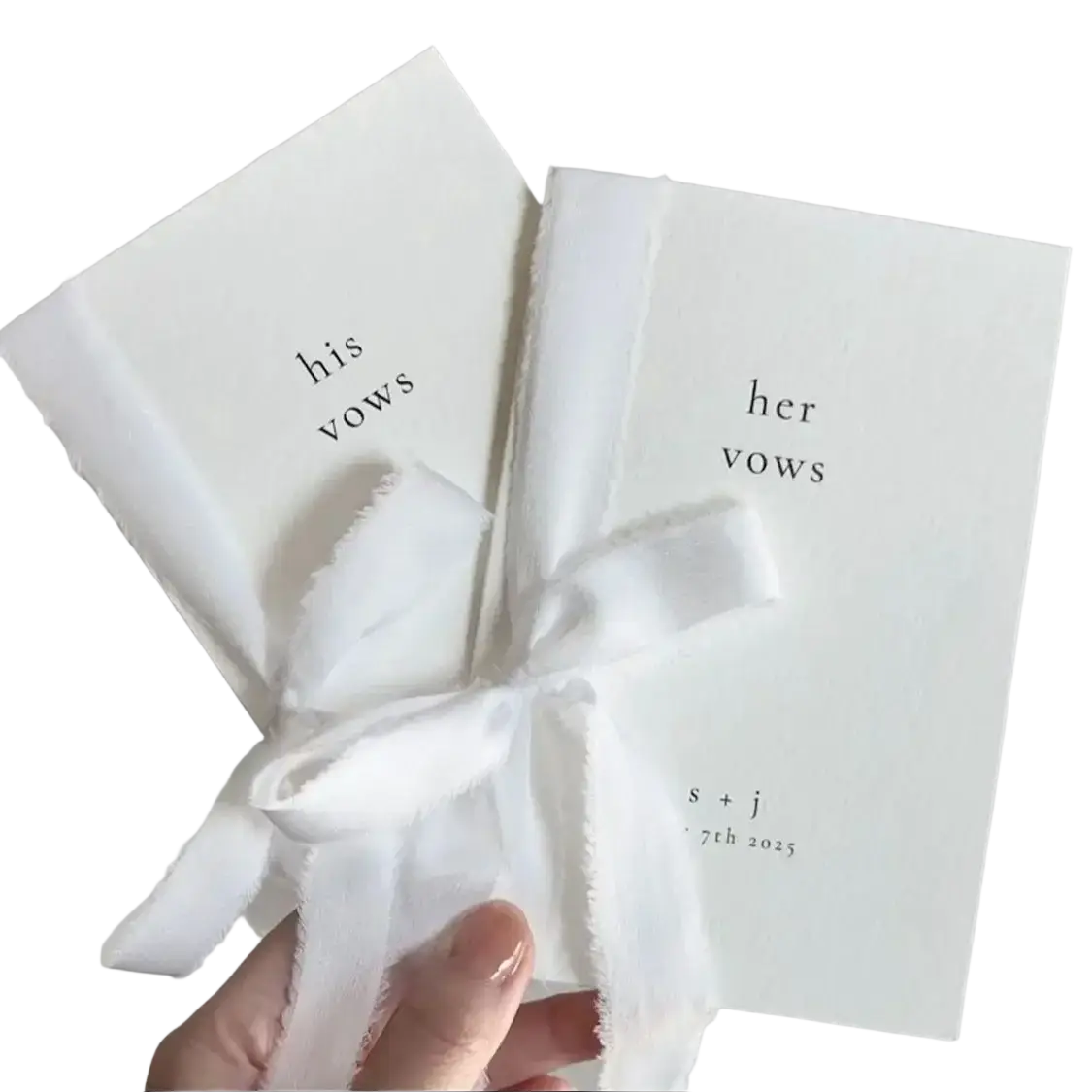 Two white personalized wedding vow books set his and her tied with a frayed white ribbon for ceremony use