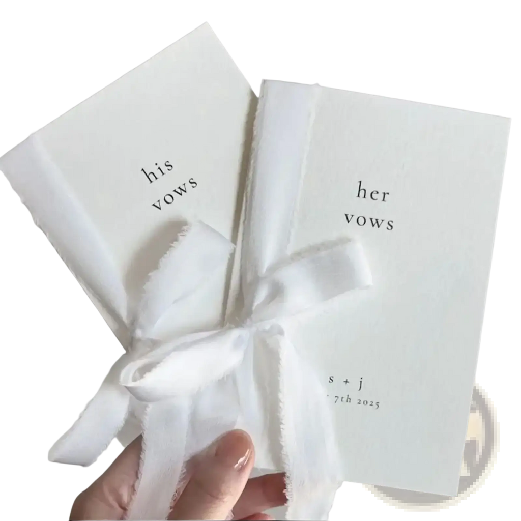 Two white personalized wedding vow books set his and her tied with a frayed white ribbon for ceremony use