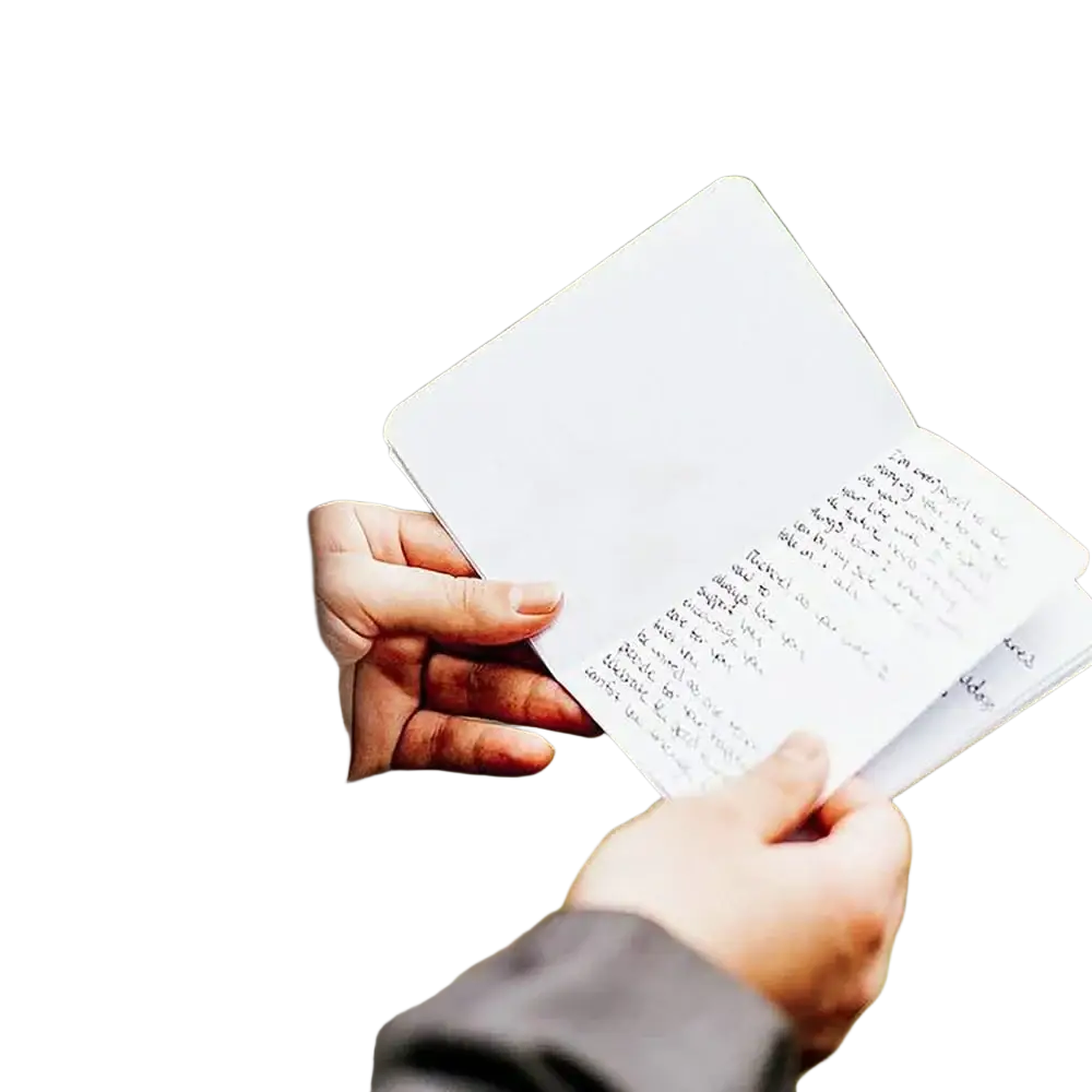A person holds an open minimalist white personalized wedding vow book with handwritten notes on its pages