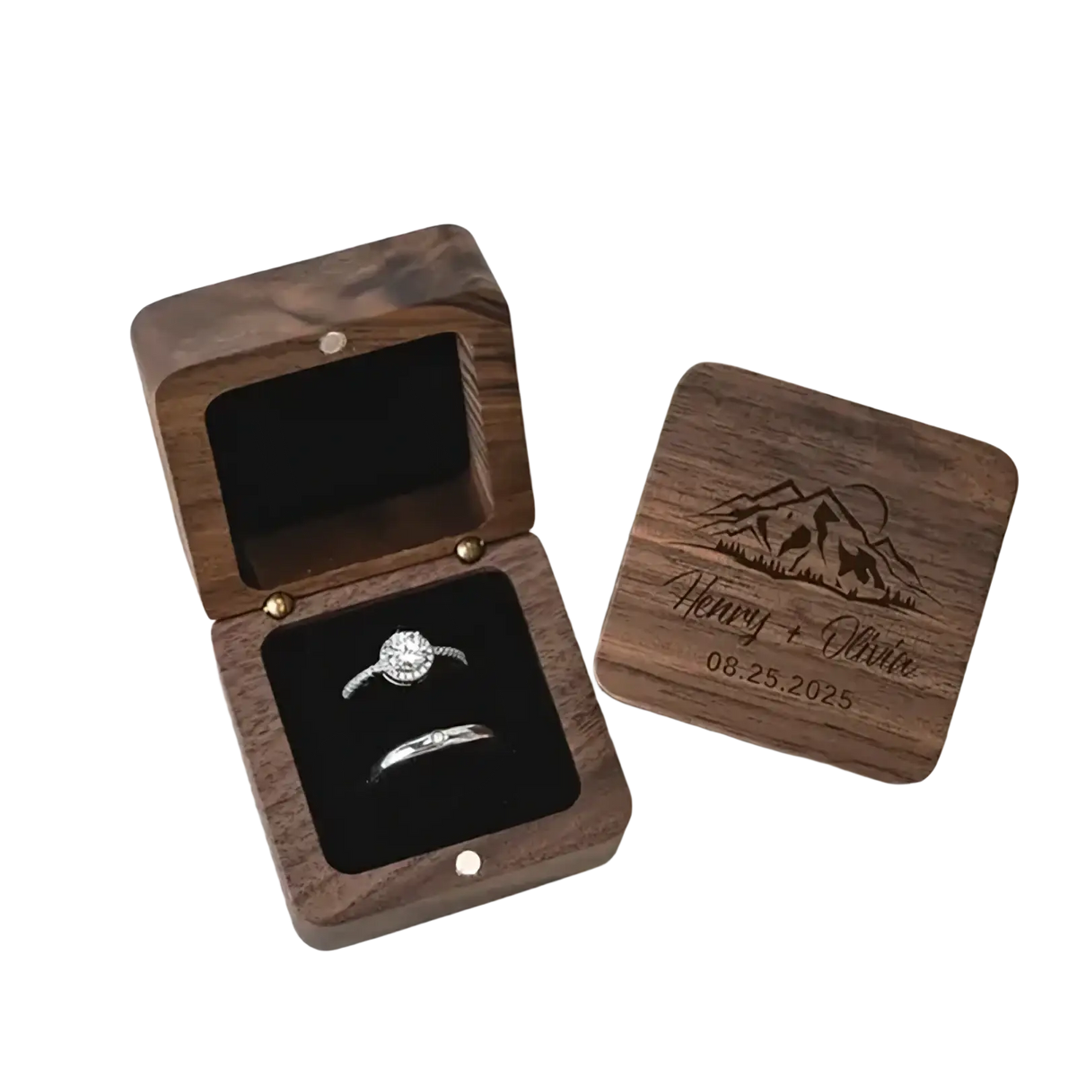 Personalized wooden wedding ring box in dark wood with engraved mountain scene and names holding diamond rings inside