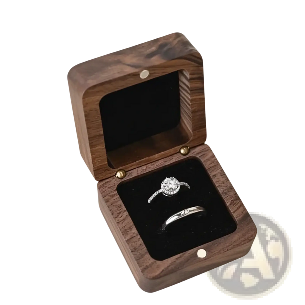 A personalized wooden wedding ring box in dark wood with a black velvet interior holding an engagement ring and band