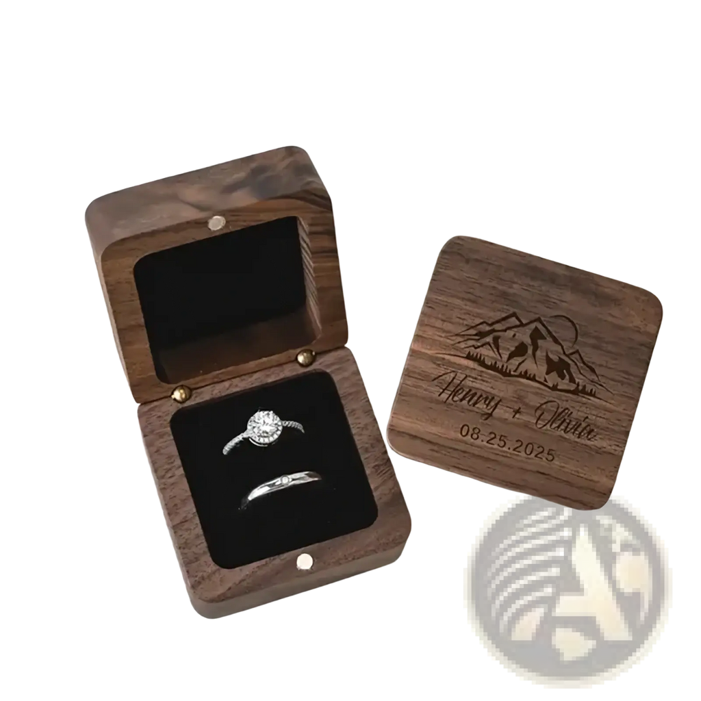 Personalized wooden wedding ring box in dark wood with engraved mountain scene and names holding diamond rings inside