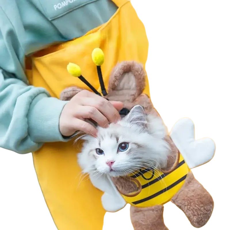 A fluffy white cat in a plush bee costume sitting inside a yellow canvas pet carrier bag with animal print