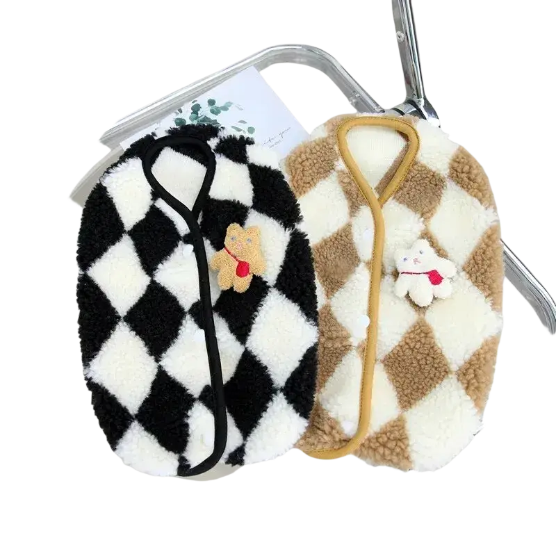 Two plush fleece vest-style pouches in black white and beige cream with diamond patterns and teddy bear charms for pet clothing