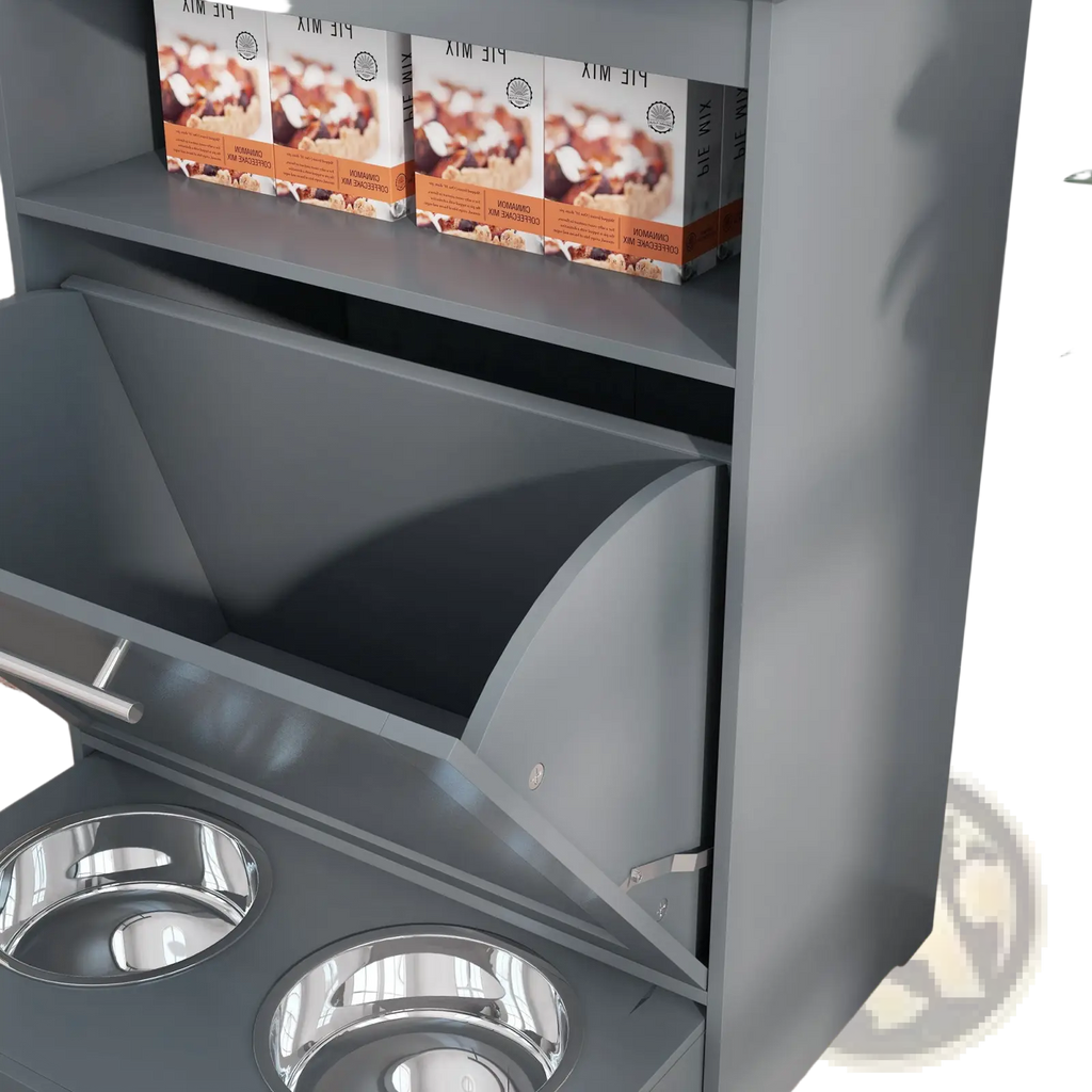 Gray metal pet feeder station with two stainless steel bowls and storage shelf holding pie mix boxes for dog food storage