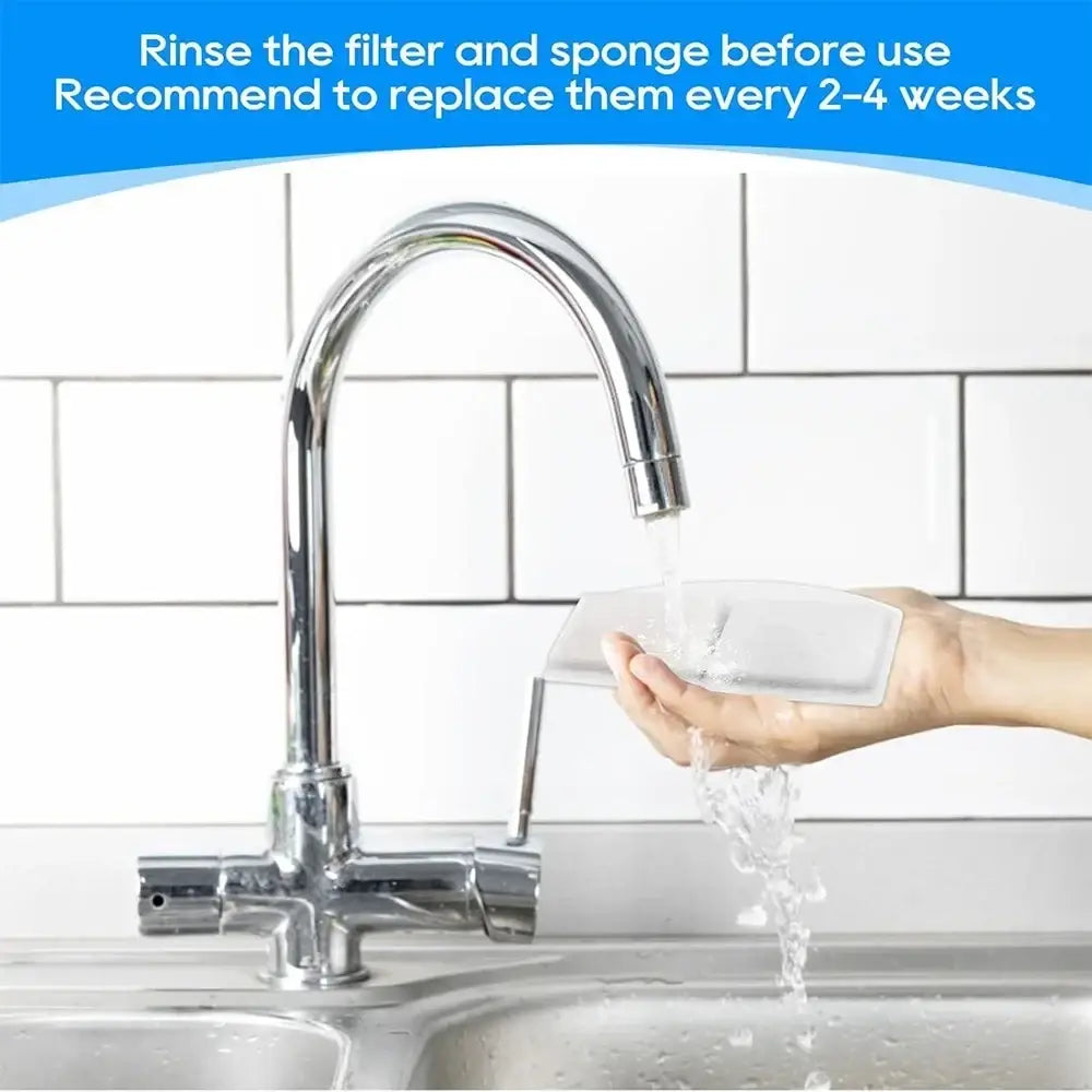 A sleek white rectangular pet water fountain filter with activated carbon and metallic handle being rinsed under water