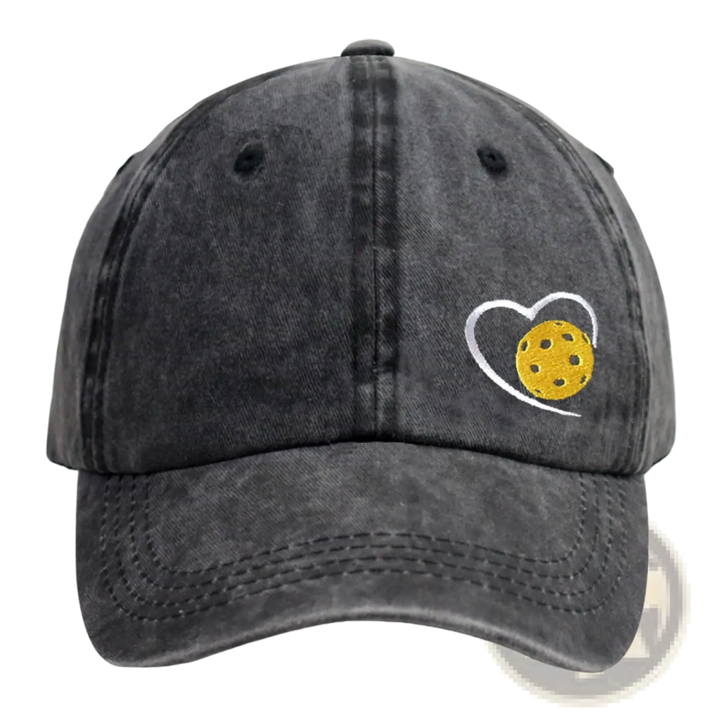 A dark gray distressed cotton baseball cap featuring a white embroidered heart outline with a yellow pickleball inside