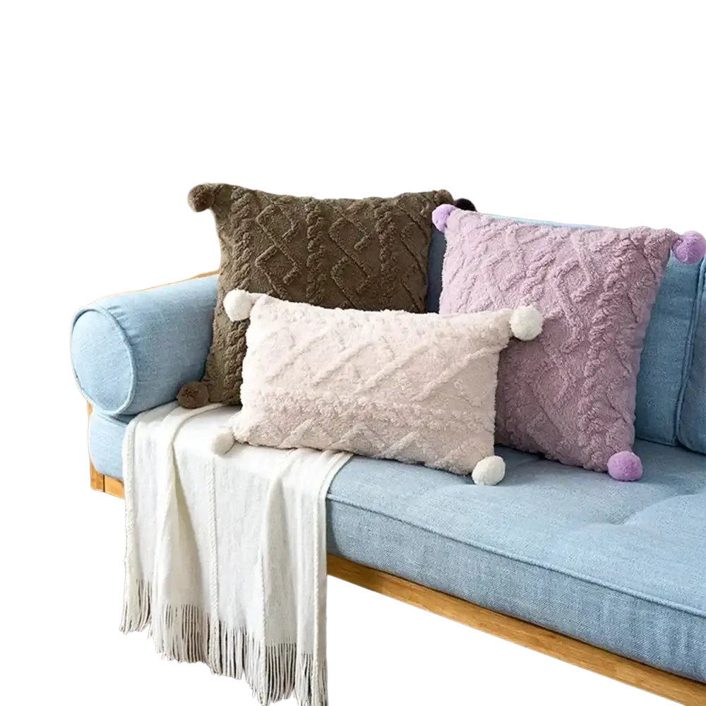 Three textured pillow covers in brown cream and lavender with pom-pom accents on a light blue sofa, 45x45cm square