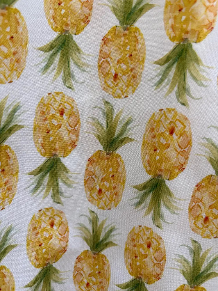 White pineapple print sleeveless skater dress with pockets featuring yellow and green watercolor pineapple pattern on fabric