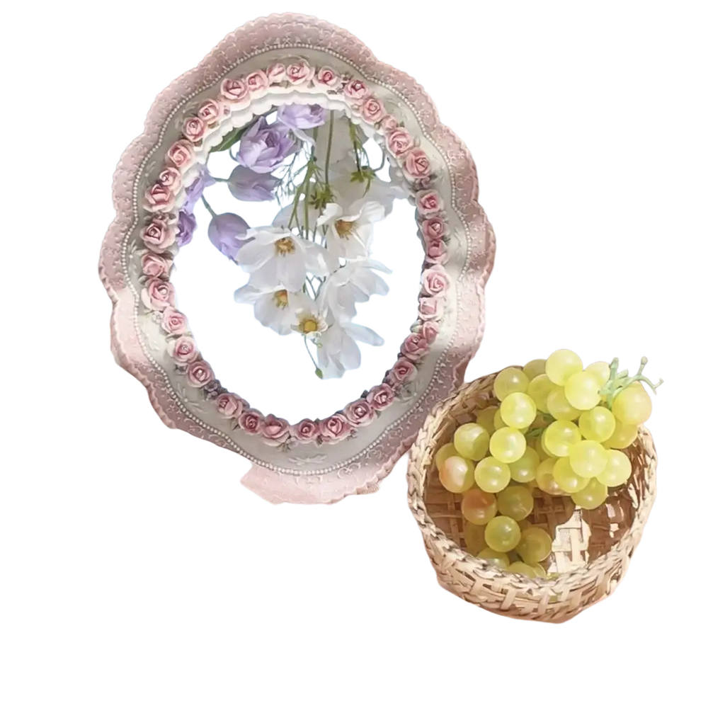 Pink baroque oval wall mirror with a silver-toned frame and delicate pink rose floral border reflecting flowers