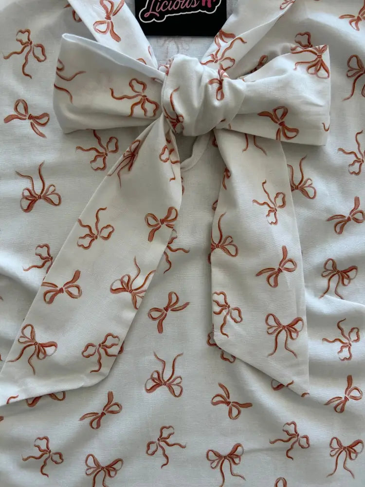 Retro pink bows sleeveless cotton blouse in white with embroidered rust-colored bow pattern and large neckline bow