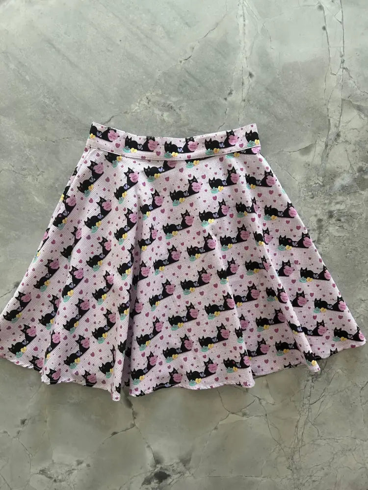 Pink cats and hearts checkered skater skirt featuring a pink pleated design with black cats and floral patterns on light fabric