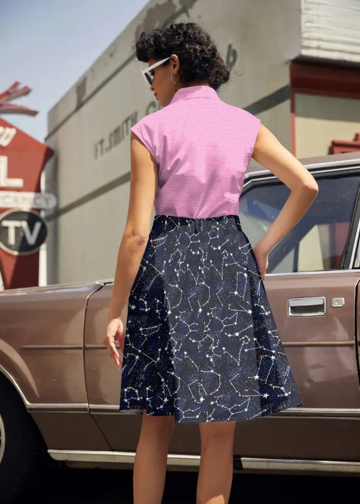 A pink sleeveless cotton top with a bow neck paired with a navy blue a-line skirt featuring a white constellation pattern