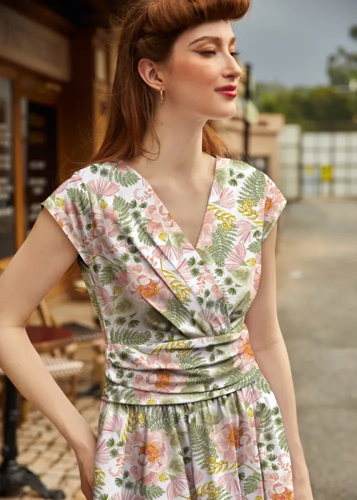 A woman wears a pink floral greta vintage cotton knee length dress with short sleeves and a v-neckline