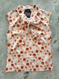 Sleeveless light pink blouse with orange and pink smiling pumpkins and stars, featuring a large bow at the collar