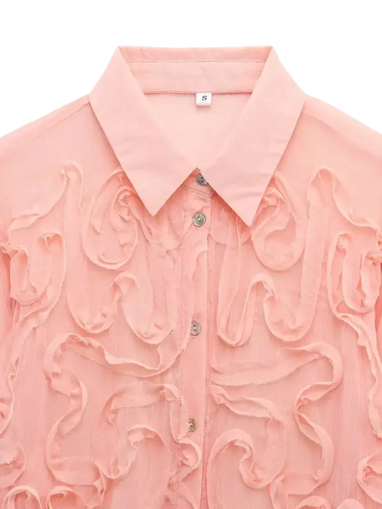 A delicate pink textured ruffled button up blouse with a classic collar and intricate swirl patterns