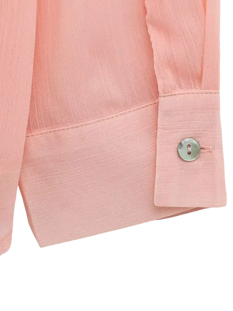 A delicate pink textured ruffled button up blouse with subtle fabric detail and a single silver cuff button