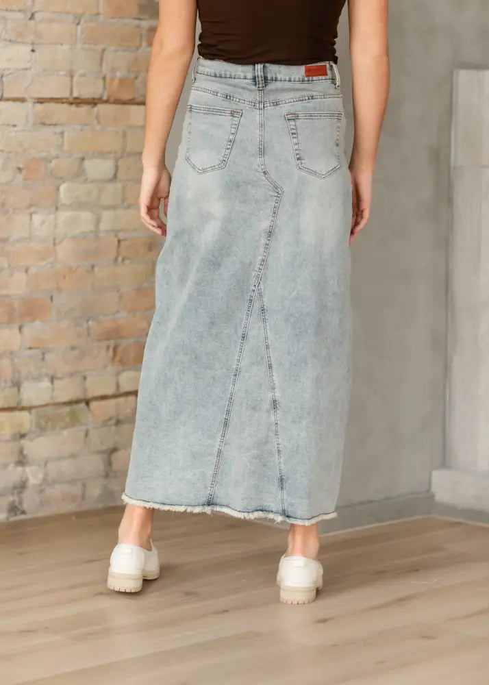 Back view of Piper light wash a-line denim maxi skirt with frayed hem and functional back pockets in light-wash denim