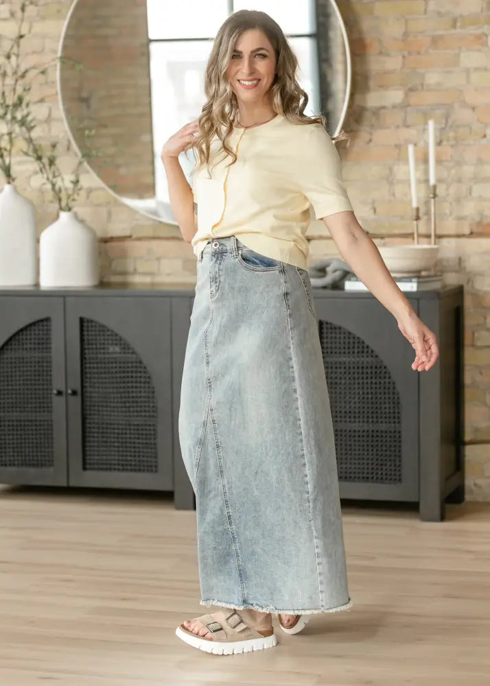 Light-wash denim maxi skirt with a straight cut and frayed hem in the back side view of the piper a-line skirt