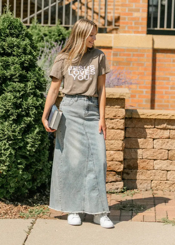 A long light-wash denim A-line maxi skirt with frayed hem and side slits in Piper style