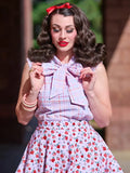 A woman wears a vintage pink plaid sleeveless blouse with a large bow at the neckline and bust darts