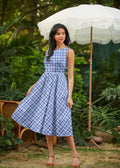 A woman wears a sleeveless blue and cream plaid 1950s cotton midi swing dress with an a-line silhouette