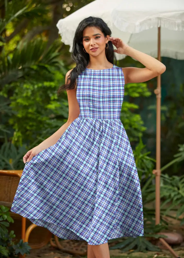 A sleeveless blue and cream plaid 1950s cotton midi swing dress with fitted bodice and flared skirt