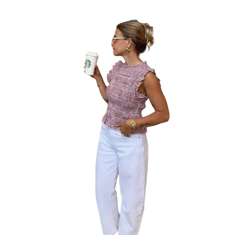 A woman wearing a pink and white houndstooth textured plaid ruffled sleeveless summer tank top
