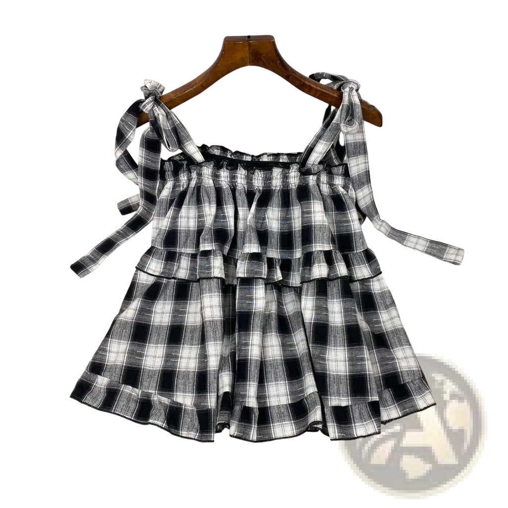 Black and white plaid tiered mini dress with adjustable bow shoulder straps in lightweight fabric for casual wear