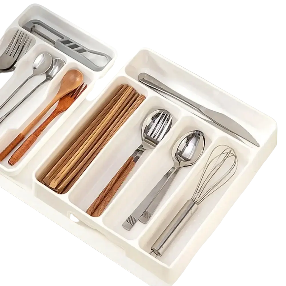 White plastic cutlery drawer organizer with segmented compartments holding wooden spoons metal forks knives and whisk