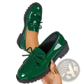 Platform tassel loafers in shiny emerald green patent leather with black rubber soles and decorative bows for casual wear