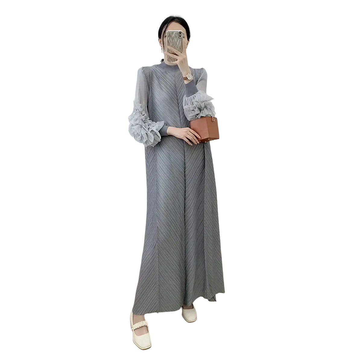 A woman wears a long gray pleated evening dress with sheer ruffled sleeves holding a small brown leather clutch