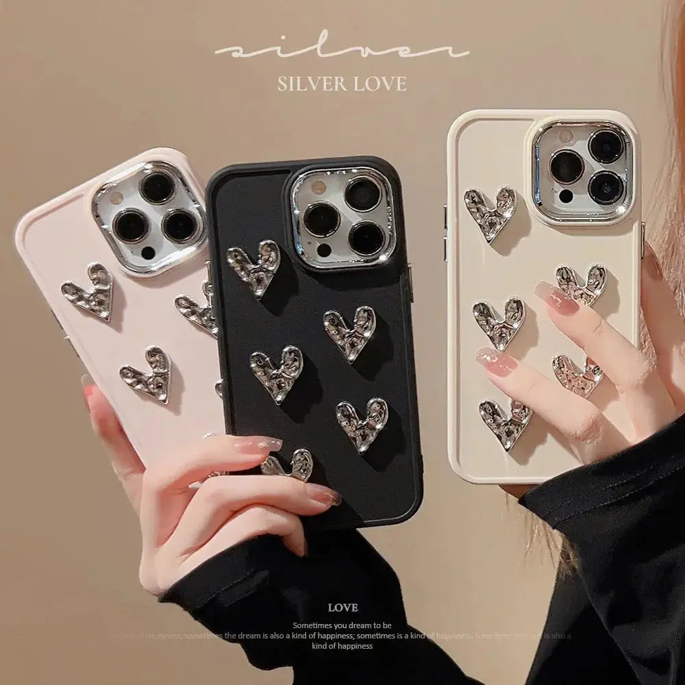 Three glossy pleated metallic heart charm phone cases with silver heart-shaped embellishments shown from the back side