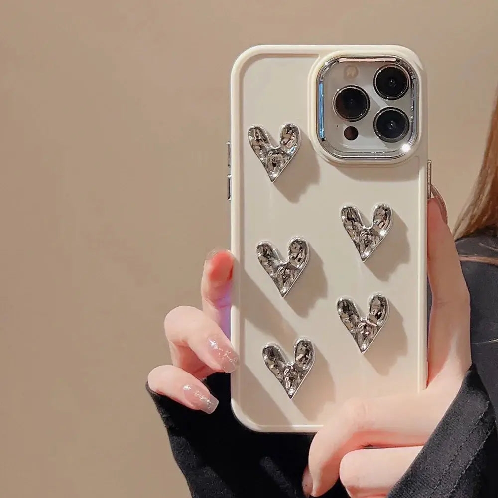 Cream-colored pleated metallic heart charm phone case with five silver textured heart embellishments shown from the back side