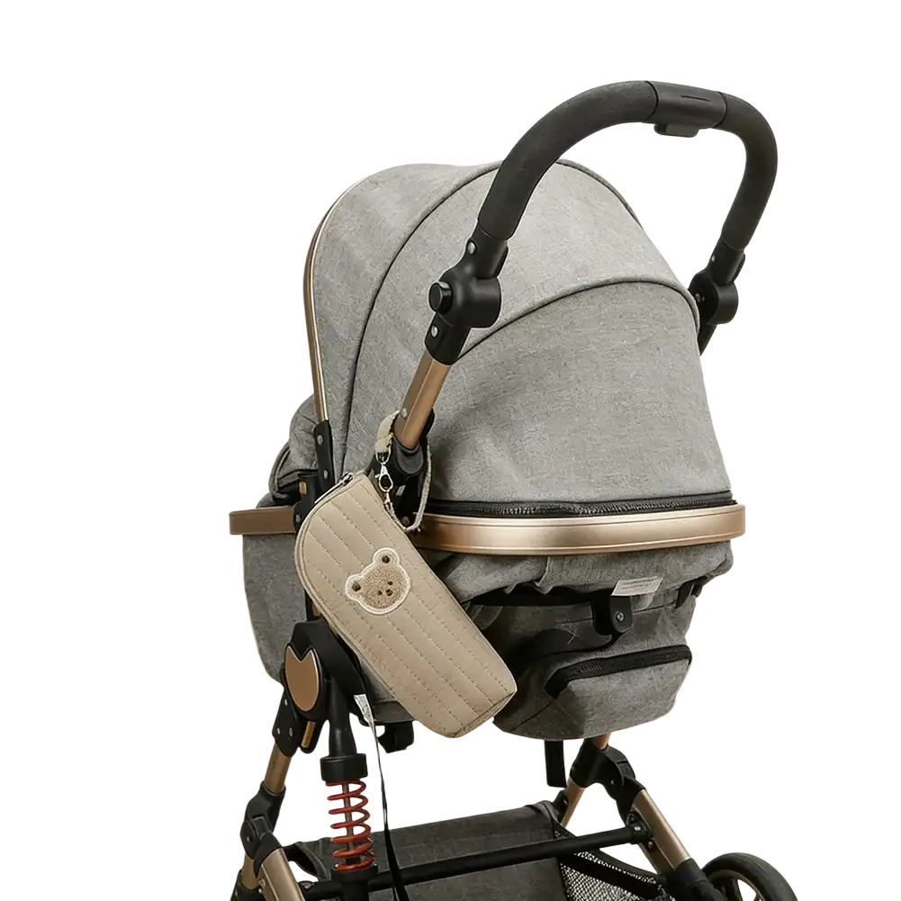 Gray fabric stroller with black and gold accents featuring quilted beige pouch for plush bear baby bottle warmer bag