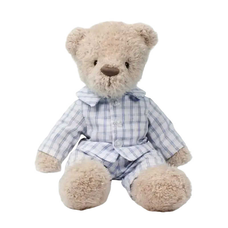 A plush bear stuffed animal in beige wearing light blue and white plaid pajamas as a sleeping toy