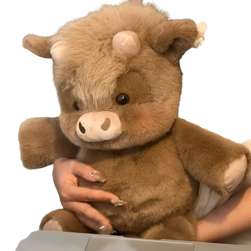 A plush brown highland cow stuffed animal with soft fur pinkish snout and ears dark eyes from plush cow and pig toys