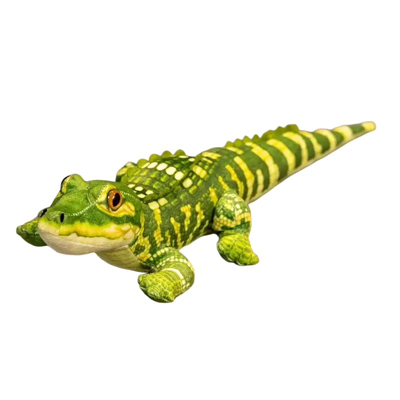 Plush crocodile stuffed animal toy in green and yellow with detailed scales and orange eyes resting on a magazine