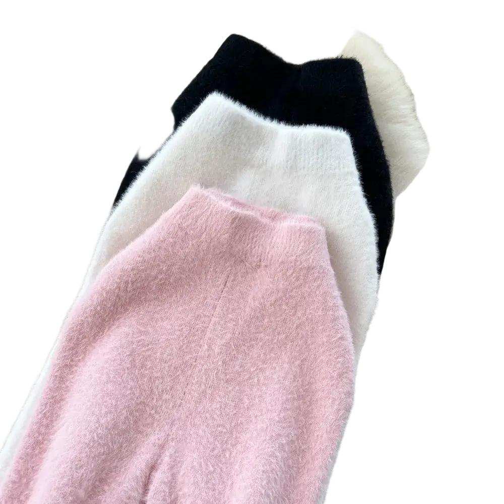 Three high waisted plush cashmere knit skirts in pink white and black displayed on white fur surface