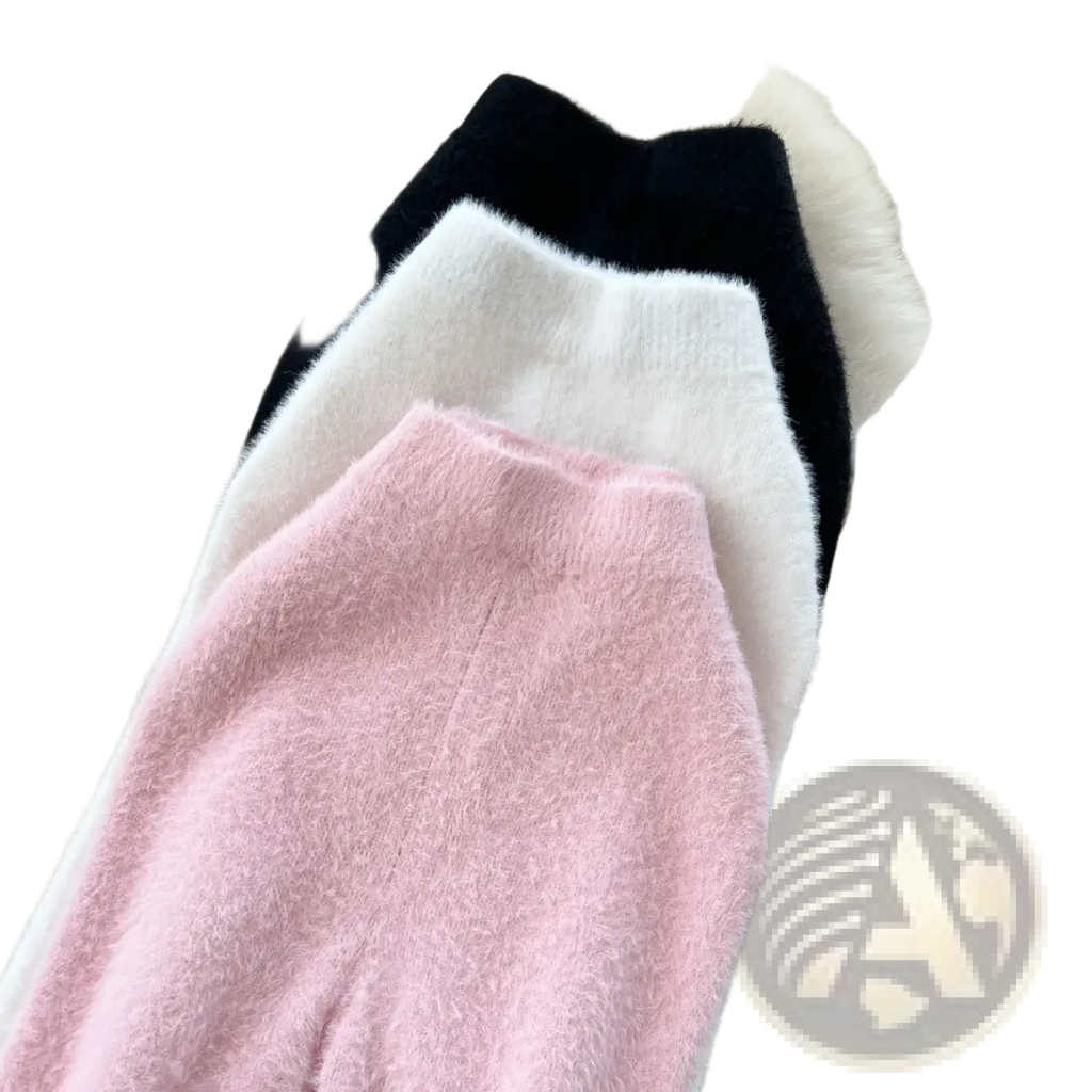 Three high waisted plush cashmere knit skirts in pink white and black displayed on white fur surface