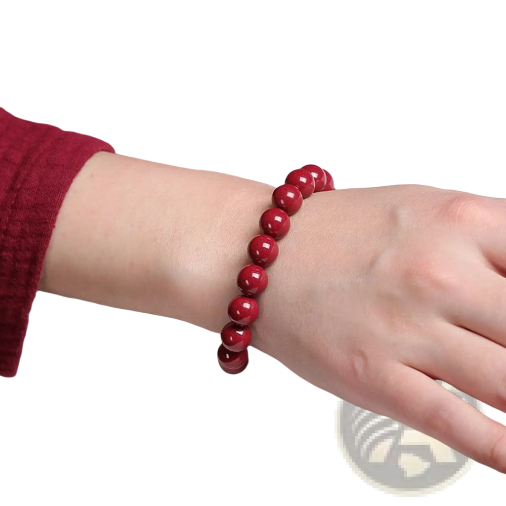 A polished red cinnabar spherical bead bracelet with a vibrant glossy finish worn on a wrist
