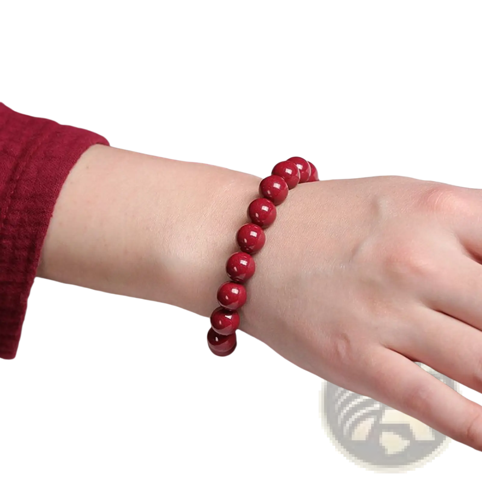 A polished red cinnabar spherical bead bracelet with a vibrant glossy finish worn on a wrist