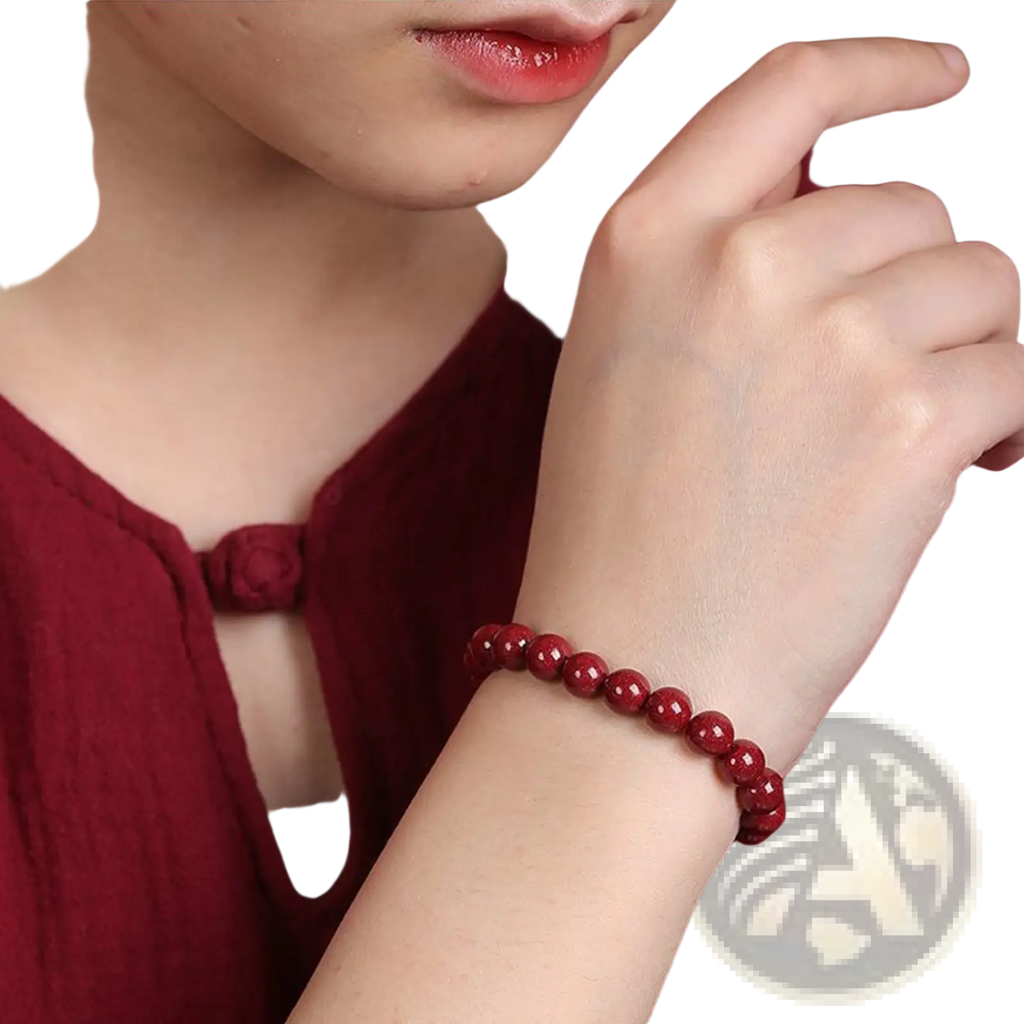 A vibrant red polished cinnabar spherical bead bracelet with a smooth surface worn on a wrist